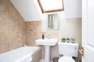 a bathroom with a sink and a toilet and a bath tub at Cosy Cottage in Beautiful South Downs Walk 2 Pub in Chichester