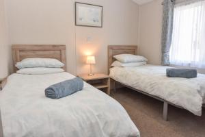 a bedroom with two beds and a lamp on a table at Long View in Roebeck Country Park, sleeps 4, beach 3.5 miles. in Ryde