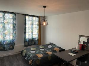 een slaapkamer met een bed, een tafel en 2 ramen bij Joli studio en cœur de ville in Limoges