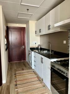 a kitchen with a sink and a dishwasher and a door at Silicon Path Spacious studio in Dubai