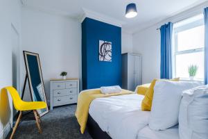a bedroom with a white bed and a yellow chair at Barnes House - Sleeping 8 in Clayton le Moors