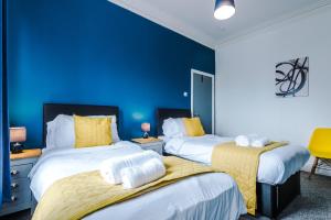 2 camas en una habitación con una pared azul en Barnes House - Sleeping 8, en Clayton le Moors