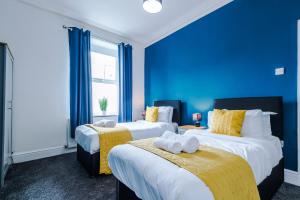 Duas camas num quarto com paredes azuis em Barnes House - Sleeping 8 em Clayton le Moors