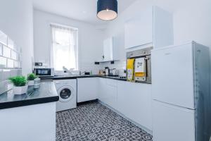Una cocina blanca con lavadora y secadora. en Barnes House - Sleeping 8, en Clayton le Moors