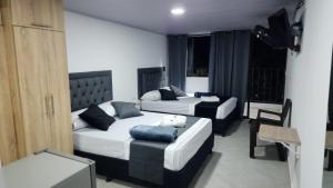 um quarto com 2 camas, uma cadeira e um sofá em Aparta estudios Estadio la 80 em Medellín