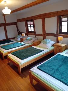 three beds in a room with wooden floors and windows at Rębiszów 50 in Rebiszów