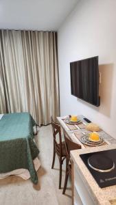 um quarto com uma cama, uma mesa e uma televisão em Studio Encantador a Beira Mar e Próximo do Centro de Convenções em Salvador