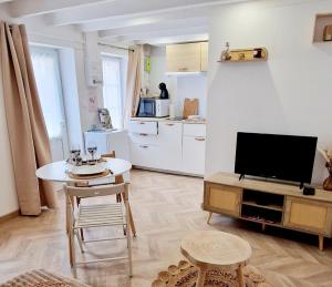 a living room with a television and a table and chairs at LaMaisonnette 500m plage Juno Beach in Bernières-sur-Mer