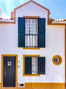 ein weißes Gebäude mit grünen Fensterläden und einem Fenster in der Unterkunft WelcomeBuddy - Casa da Praia - Moinhos Beach in Porto Formoso