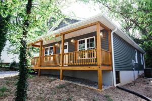 a tiny house with a large deck in the woods at Farmville Modern Farmhouse in Farmville