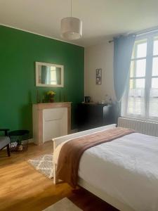 Le VigeantにあるMaison du Vergerの緑の壁、ベッド付きのベッドルーム1室
