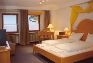 a bedroom with a bed and a desk and two windows at Burghotel Volmarstein in Wetter