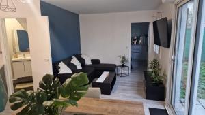 a living room with a black couch and some plants at Joli appart à 10mn de paris in Bezons +3 photos