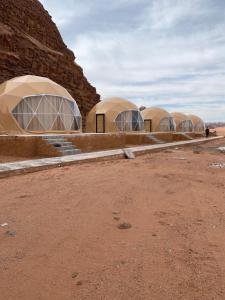 Une rangée de cinq dômes dans un champ désertique dans l'établissement Feras Camp Wadi Rum, à Wadi Rum