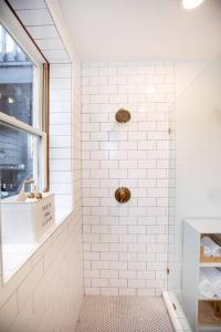a white tiled bathroom with a shower with a window at Farmville Modern Loft in Farmville