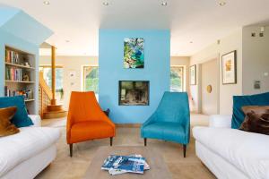 uma sala de estar com paredes azuis e cadeiras laranja em Secluded barn style home with hot tub - sleeps 12 em Birdham