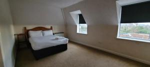 um pequeno quarto com uma cama e 2 janelas em Reading Budget Apartments em Reading