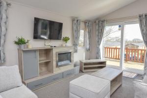 a living room with a fireplace and a tv at Rowan a welcoming countryside lodge in Ryde