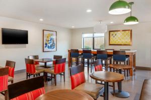 a restaurant with tables and chairs and a tv at Comfort Suites Whitsett - Greensboro East in Whitsett