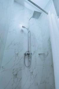 a shower in a bathroom with white marble tiles at The Keza Hotel Botique in Kigali