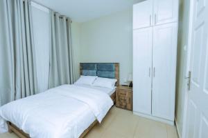 a white bedroom with a bed and a closet at Nice Homes Villa in Kigali