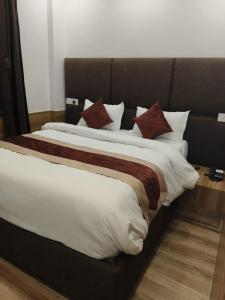 uma cama grande com lençóis e almofadas castanhos e brancos em Hotel Obsidian Red em Gorakhpur