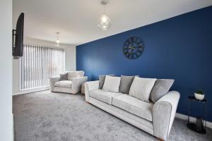 uma sala de estar com um sofá e um relógio numa parede azul em Host & Stay - Marsden Beach House em South Shields