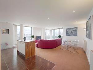 London ExCeL Stays - Three Bed Serviced Apartment في لندن: غرفة معيشة مع أريكة حمراء وطاولة