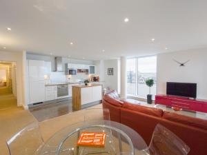 London ExCeL Stays - Three Bed Serviced Apartment في لندن: غرفة معيشة مع أريكة ومطبخ