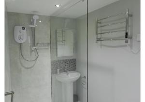 a white bathroom with a shower and a sink at Cosy Studio in Milton Keynes