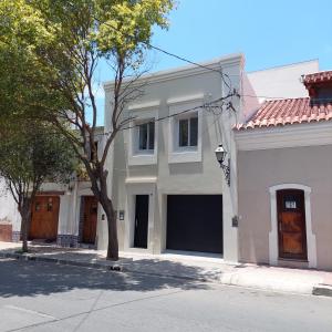 una casa blanca con un árbol delante de una calle en Departamento Salta - Calle Santiago en Salta