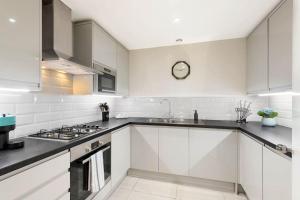 a white kitchen with a sink and a stove at Beautiful Royal Borough Apartment in London