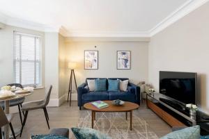 a living room with a blue couch and a table at Beautiful Royal Borough Apartment in London