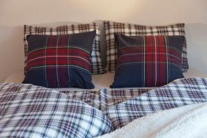 two plaid pillows sitting on top of a bed at Exklusives Landhaus in den Bergen in Arzl im Pitztal