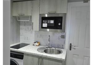 a kitchen with a sink and a microwave at Cosy Studio in Milton Keynes