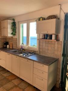 a kitchen with white cabinets and a sink and a window at House Lovre in Tkon