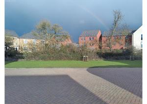 a group of brick buildings with a rainbow in the sky at Cosy Studio in Milton Keynes