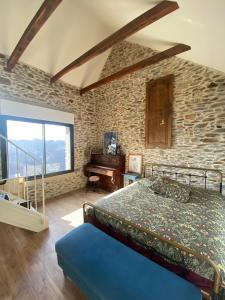 1 dormitorio con pared de piedra, cama y piano en La tête dans les nuages, en Le Fel