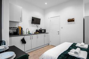 a white room with a bed and a kitchen at Modern Studio Rooms in Wembley in London