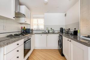 a white kitchen with white cabinets and a sink at Historic Joseph Conrad House in Heart of London! in London