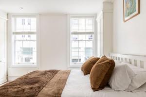 a white bedroom with a bed with two windows at Historic Joseph Conrad House in Heart of London! in London