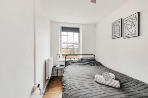 a white bedroom with a bed and a window at Sleek Shoreditch Hideout - 2 Bed Gem with Balcony in Central London in London