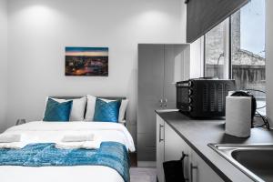 Modern Studio Rooms in Wembley في لندن: غرفة نوم بسرير ومخدات زرقاء ومغسلة