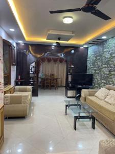 Mangala stay home (Malleshwaram) Ground Floor Apts في بانغالور: غرفة معيشة مع كنب وتلفزيون بشاشة مسطحة