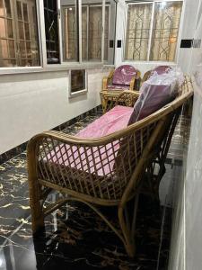 Mangala stay home (Malleshwaram) Ground Floor Apts في بانغالور: مقعد الخوص في غرفة مع نوافذ