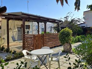 un patio con mesa, sillas y una valla en House Near The Beach (Militsa & Aggeliki) en Pervolia