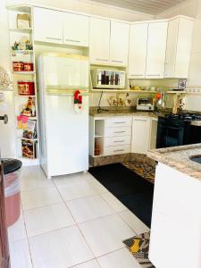 a kitchen with white cabinets and a white refrigerator at Aconchego na montanha com BANHEIRA de imersão e 5 suítes 7,5km do centro Águas de Lindóia in Águas de Lindóia