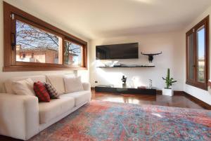 un soggiorno con divano bianco e TV a schermo piatto di Welc-oM Villa Noventa Padovana a Noventa
