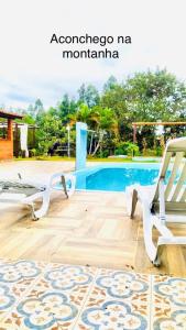 a patio with two chairs and a swimming pool at Aconchego na montanha com BANHEIRA de imersão e 5 suítes 7,5km do centro Águas de Lindóia in Águas de Lindóia