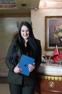 a woman with long black hair holding a blue laptop at Hotel Villa Fernando Tirana in Tirana